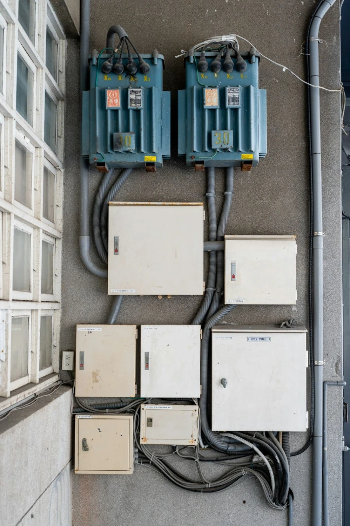 Electrical boxes and transformers mounted on a wall.